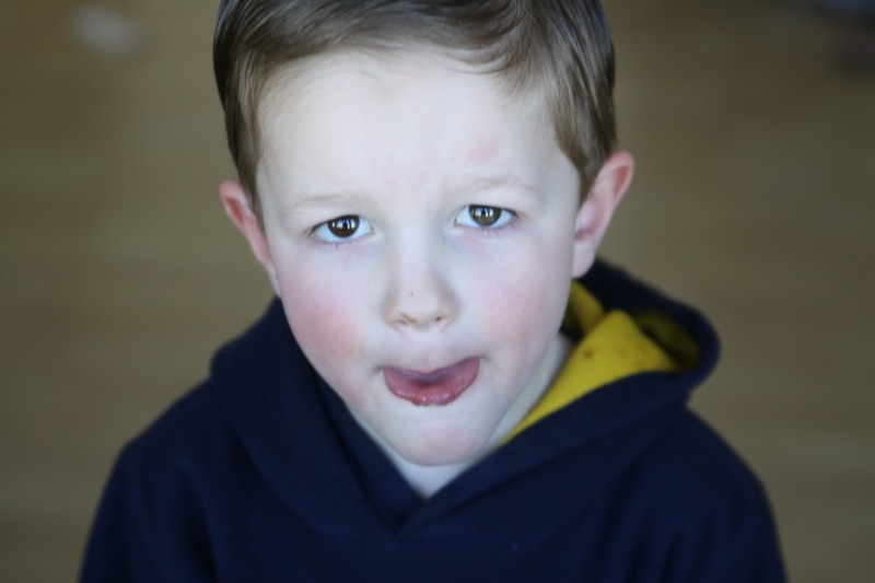 A little boy looking toward a window, face is light