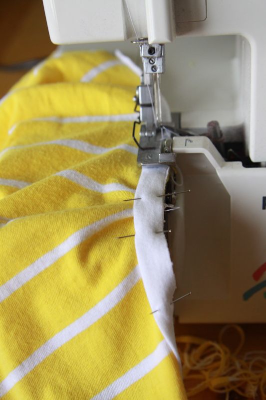 White fabric strip pinned over yellow fabric on sewing machine, yellow fabric bunched up