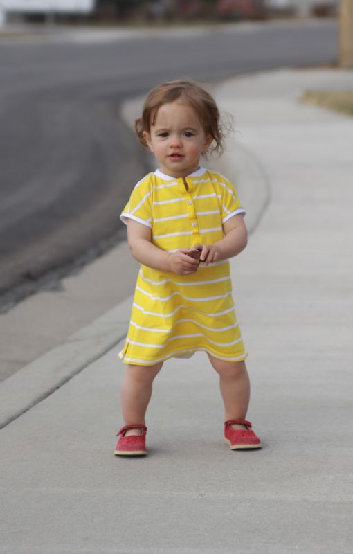 A baby girl standing on the sidewalk