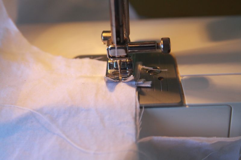 sewing across white fabric with loop of elastic sandwiched in it on a sewing machine