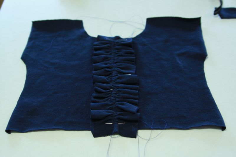 strip of fabric ruffle up with gathering stitched and pinned to center of bodice front