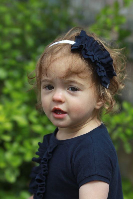 A little girl wearing a headband with ruffle on it