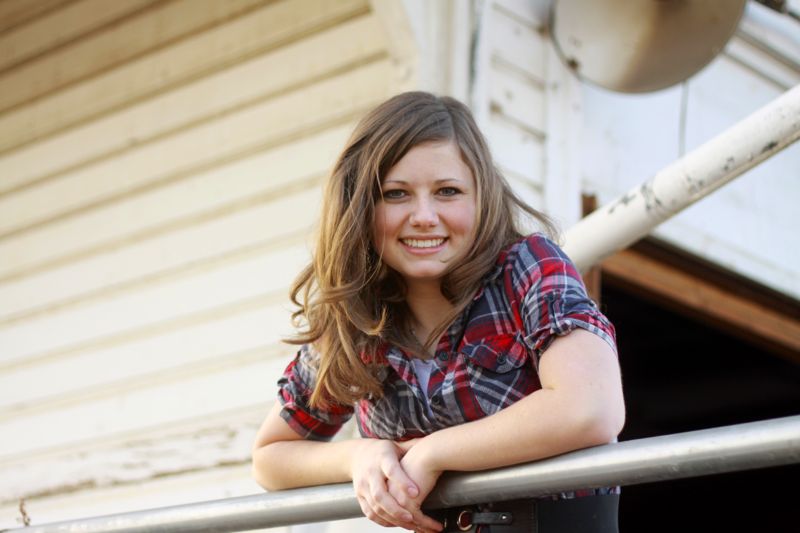 photo pose for girls: a girl leaning forward on a railing