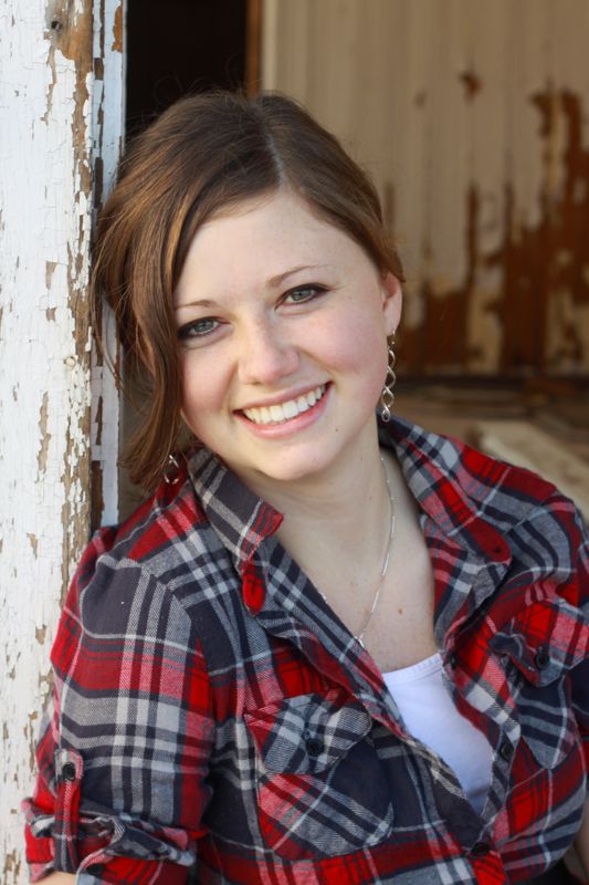 A girl leaning back against a wall, smiling at the camera