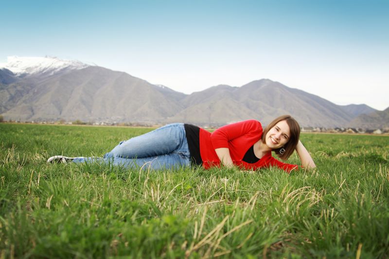 A girl lying on her side in the grass with her head on her hand