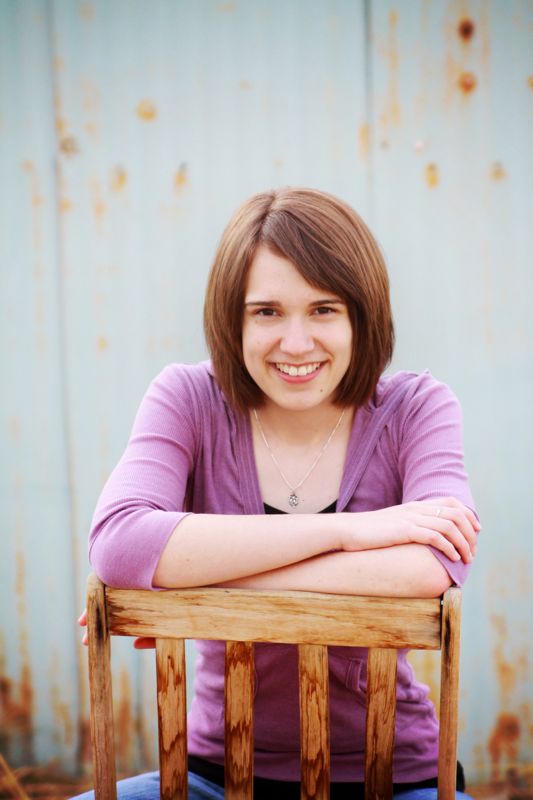 A girl sitting backwards on a wooden chair