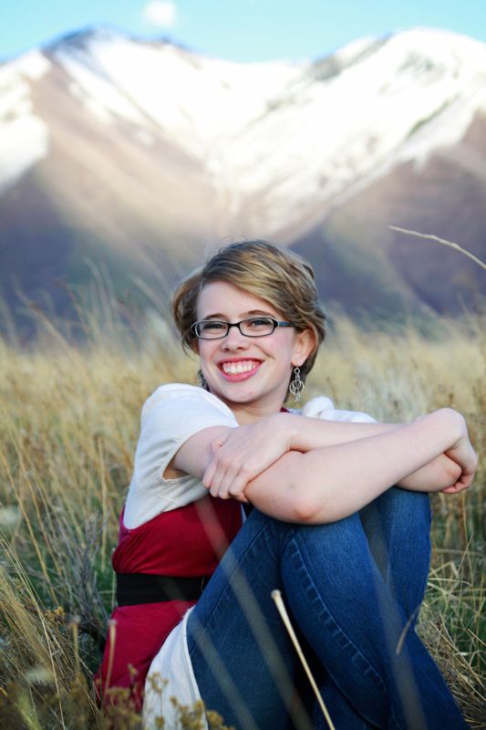 photo poses for girls: girl sitting in a field with her arms around her knees