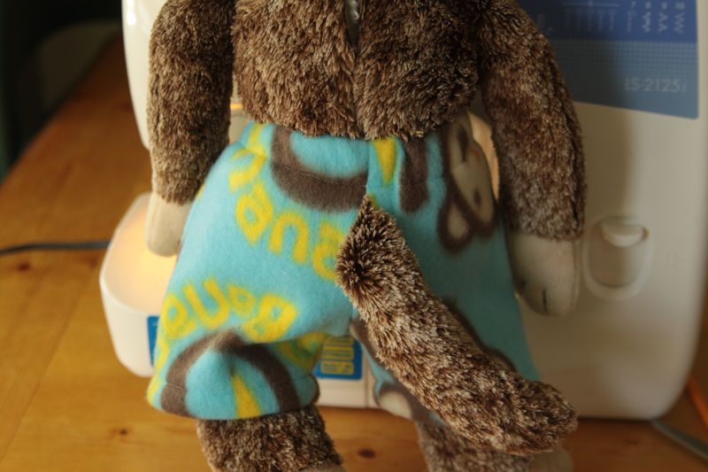 A stuffed animal monkey with tail coming out of back of shorts