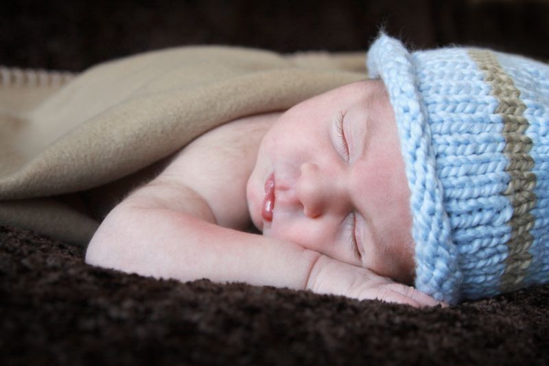 A closeup of a newborn baby wearing a blue hat