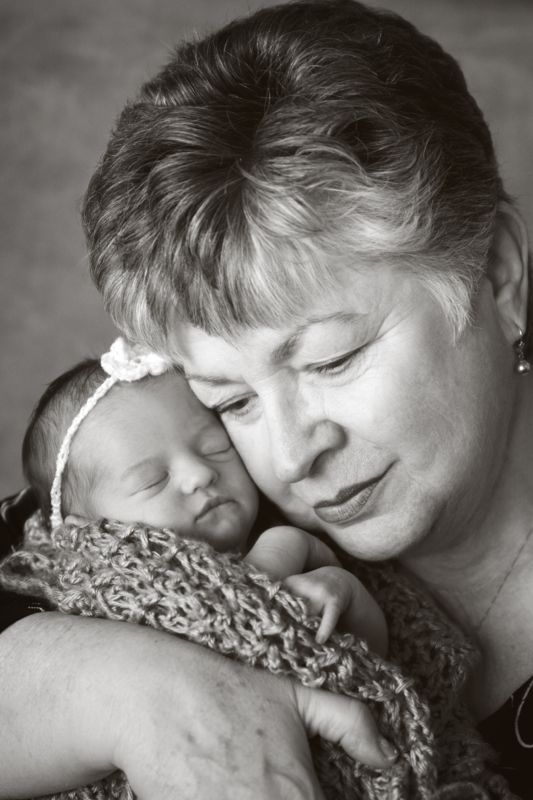 A Grandma leaning her head toward a newborn baby
