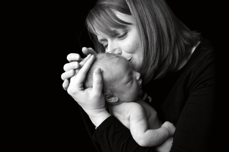 A mother kissing her newborn baby