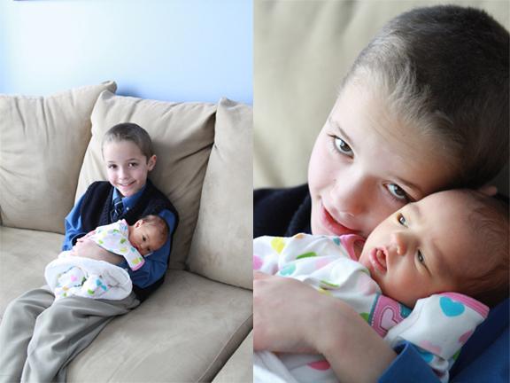 A boy holding his little sister who is a baby