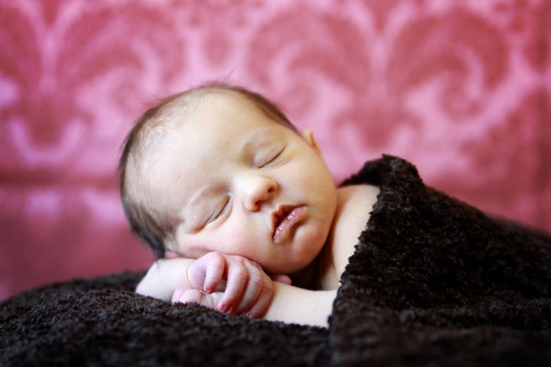 A baby lying on a blanket, resting her head on her arm