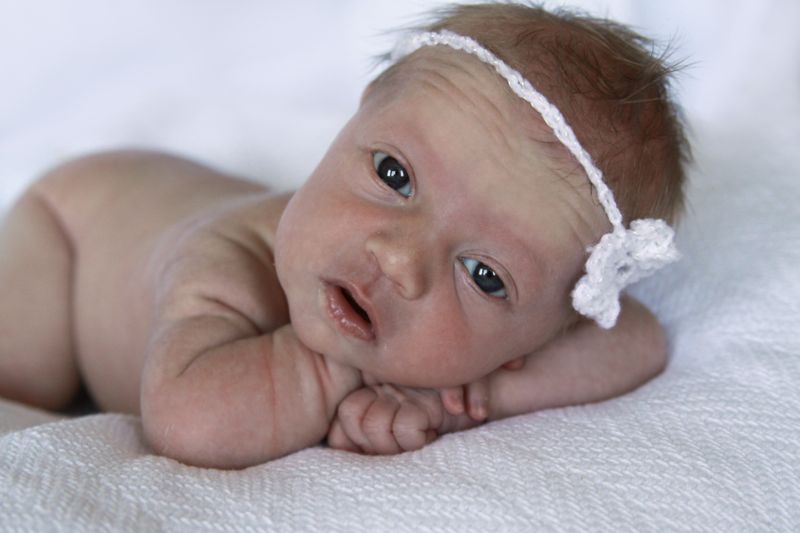 A newborn baby lying on a bed looking up at the camera