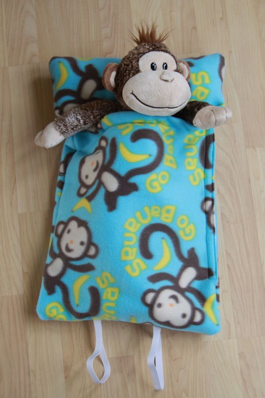 A stuffed animal monkey inside homemade fleece sleeping bag
