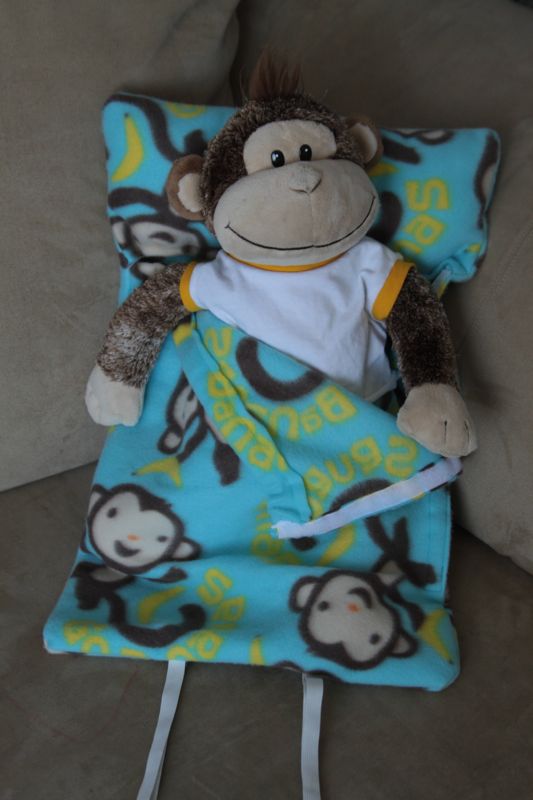 Stuffed monkey propped up inside a sleeping bag