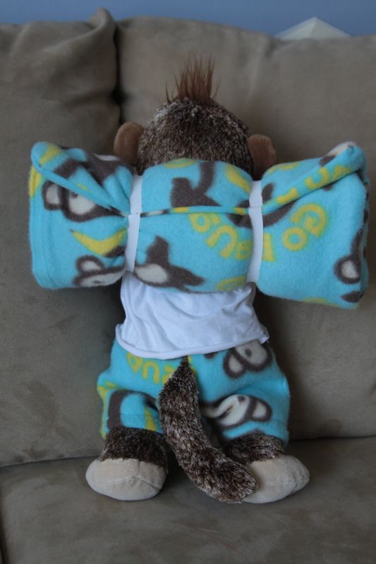 Stuffed animal monkey with sleeping bag rolled up on his back like a backpack
