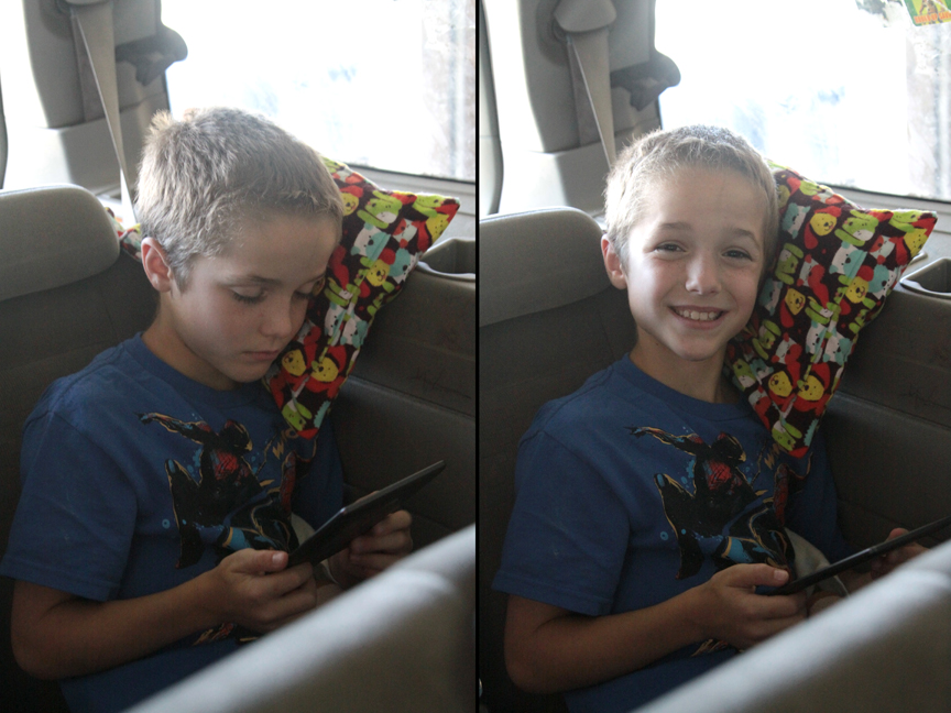 A young boy in a car leaning his head against small pillow