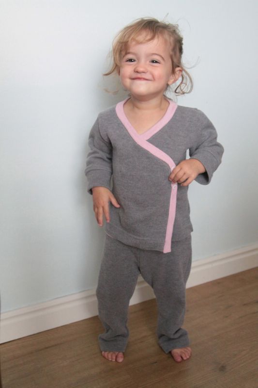 A little girl wearing gray and pink pajamas