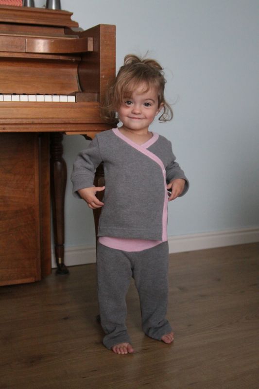 A little girl wearing a pair of wrap top pajamas made from a mens sweater