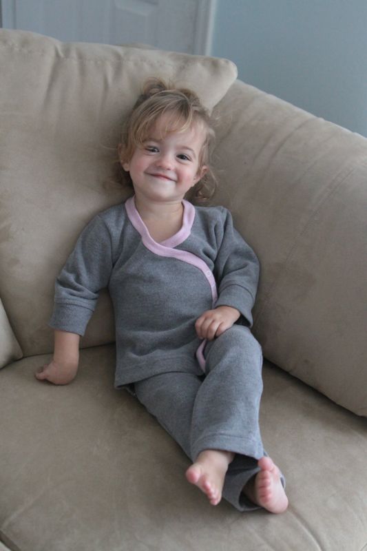 a little girl wearing gray pajamas with pink trim