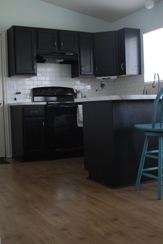 A kitchen with an island, cabinets painted black