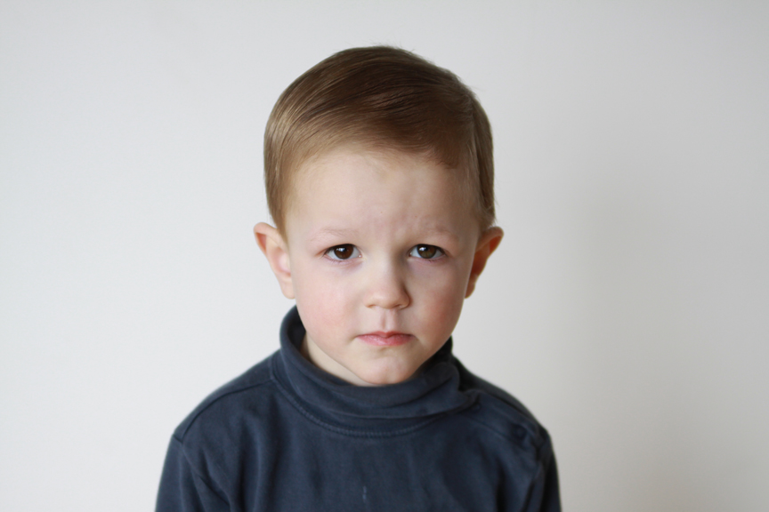 A young boy with a sad expression looking at the camera