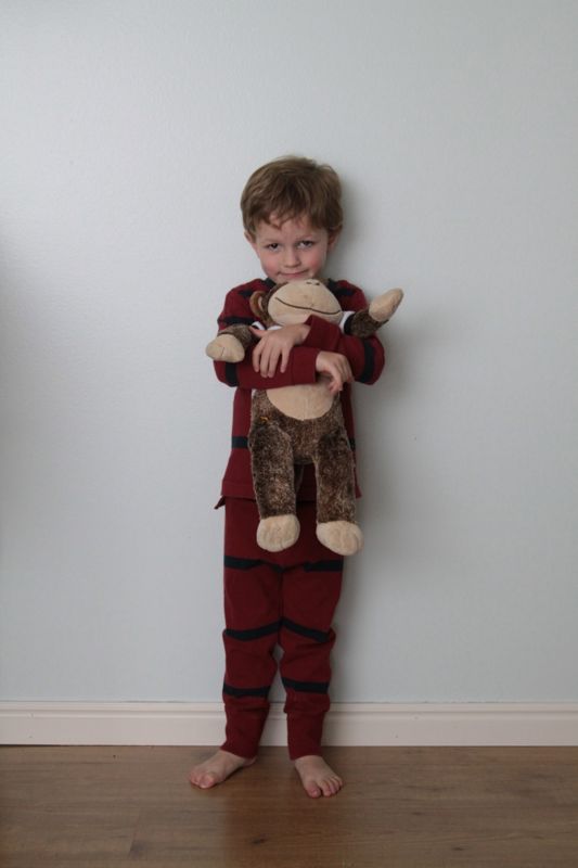 Little boy in pajamas hugging stuffed monkey