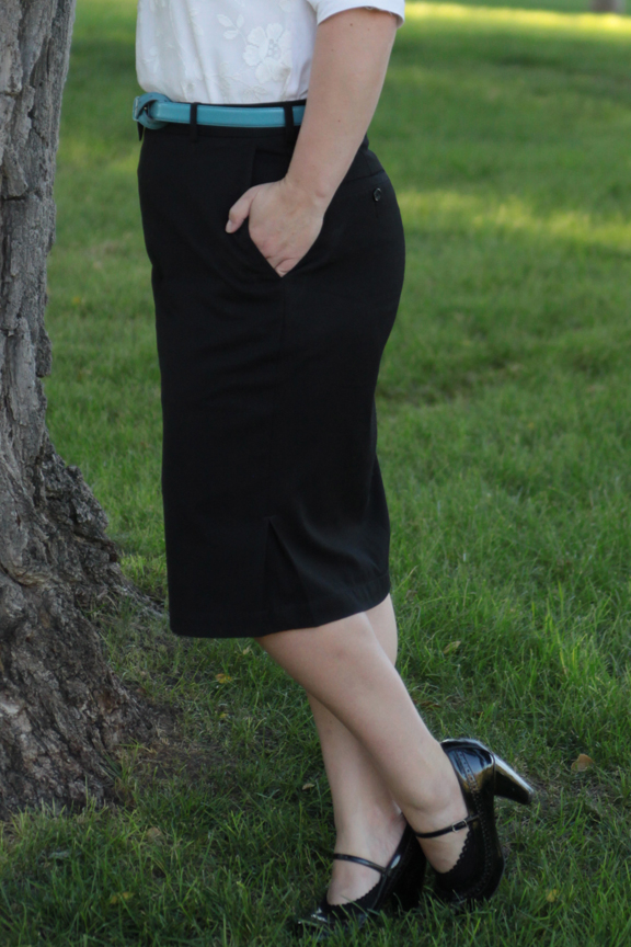 A woman wearing a black pencil skirt standing in the grass