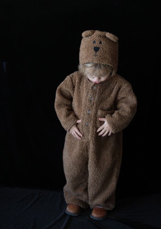 A little girl dressed up like a teddy bear in front of a black background