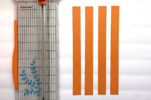 Four orange paper strips and a paper trimmer