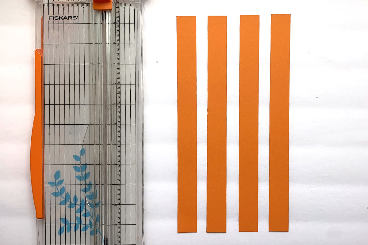 Four orange paper strips and a paper trimmer