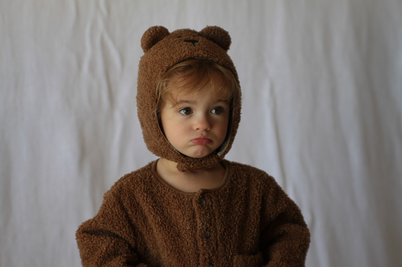 A baby girl in a teddy bear costume with wrinkled blanket background
