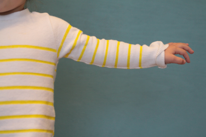 Close up of a white sweater sleeve with narrow yellow stripes