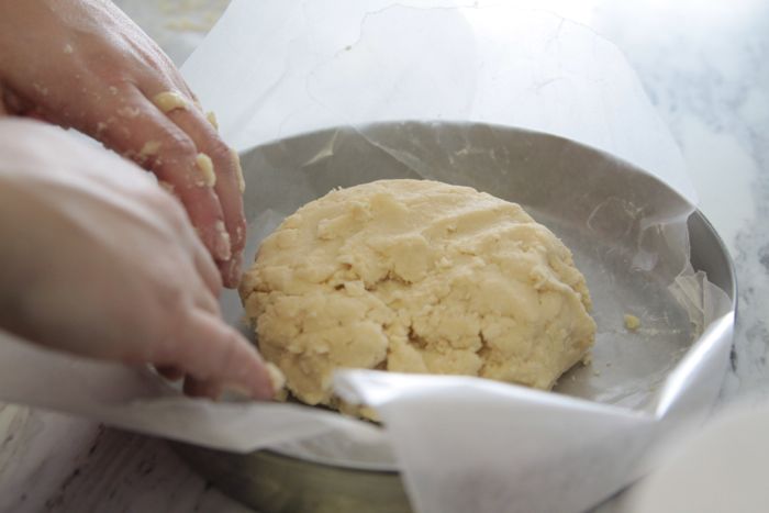 shortbread dough inside a round cake tin lined with wax paper