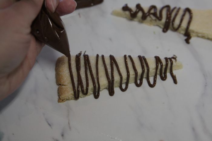 drizzling chocolate over pieces of shortbread