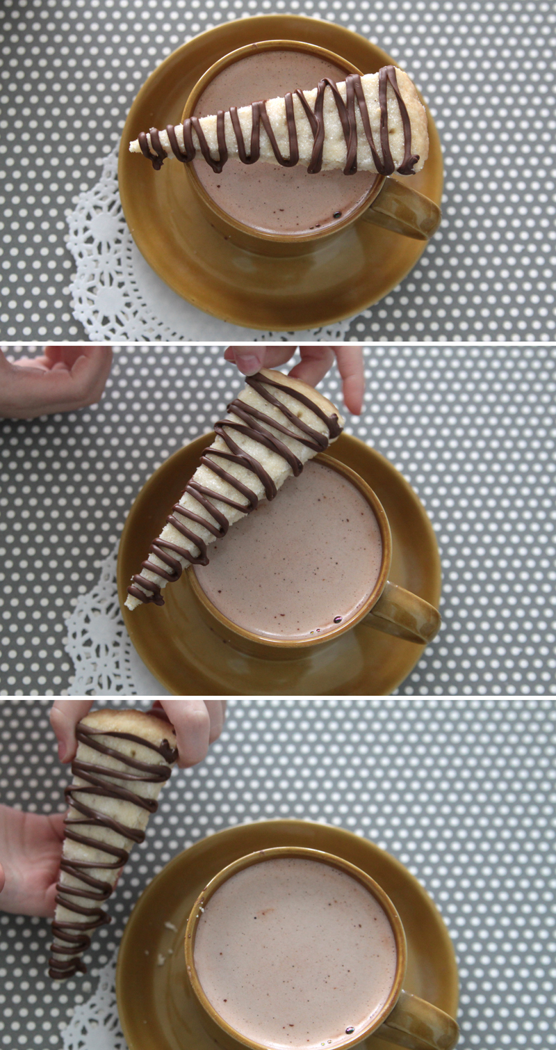 A wedge of shortbread with chocolate drizzled over it and a cup of cocoa