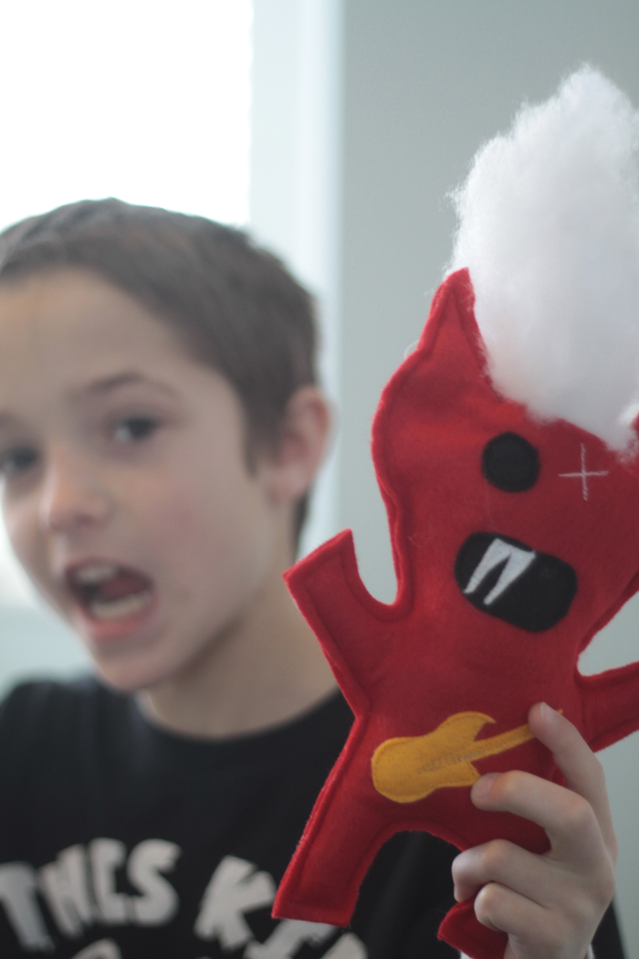 Boy holding a felt monster toy he made