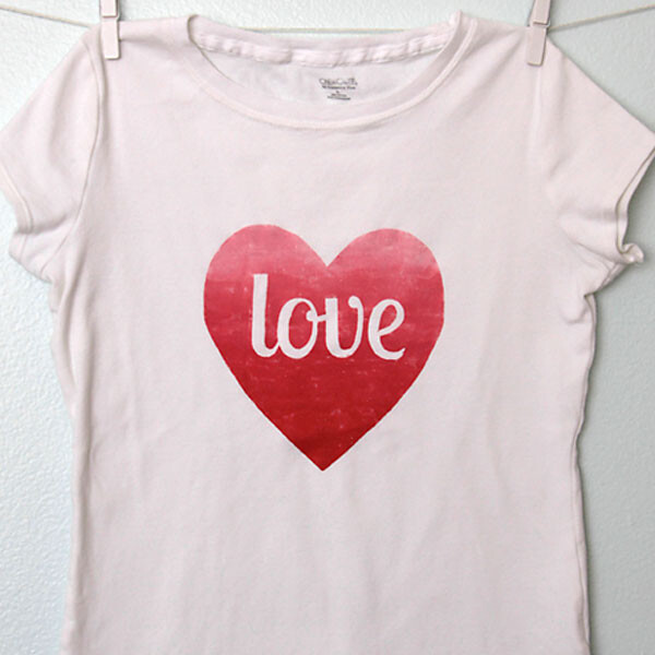 A t-shirt hanging on a line with a red heart and the word love on it