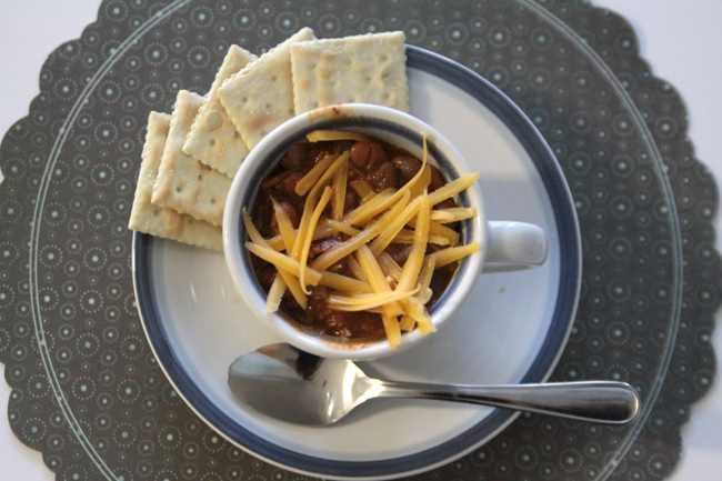 chili in a teacup with cheese and crackers