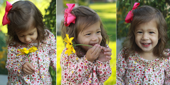 A little girl holding a flower and smiling