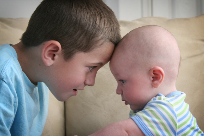 A young boy sitting near a baby