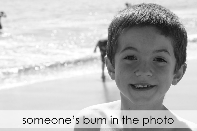 photo of a boy at the beach with another little boy right behind his head