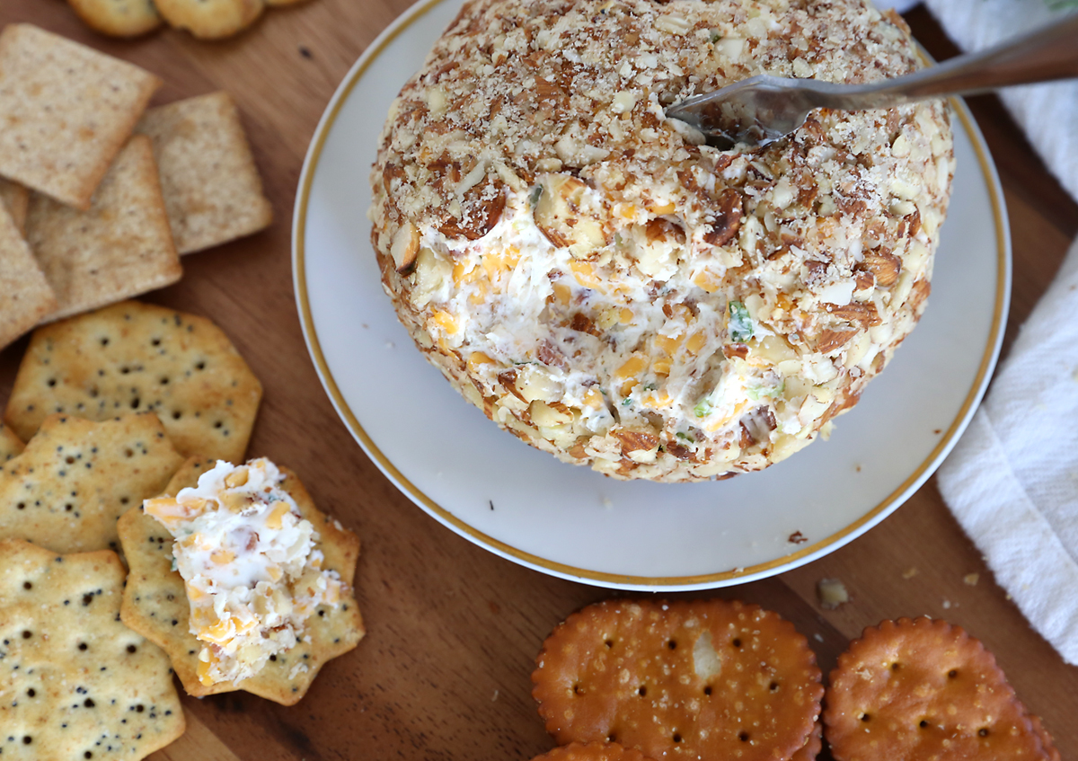 Bacon ranch cheeseball covered in chopped almonds on a plate with crackers