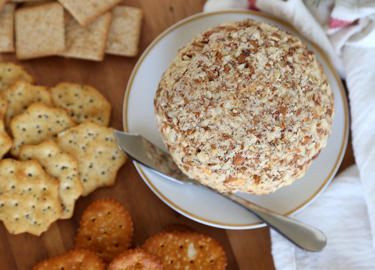 Bacon ranch cheeseball covered in chopped almonds on a plate with crackers