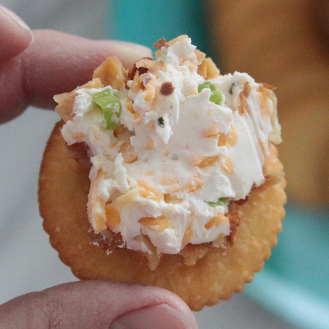 A Ritz cracker with bacon ranch cheeseball on it