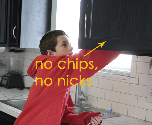 A boy reaching into kitchen cabinets
