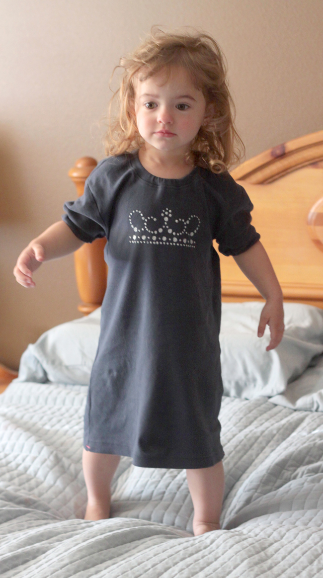 A little girl standing on a bed in an upcycled nightgown