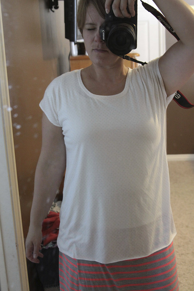 A person standing in front of a mirror wearing a handmade t-shirt taking a selfie