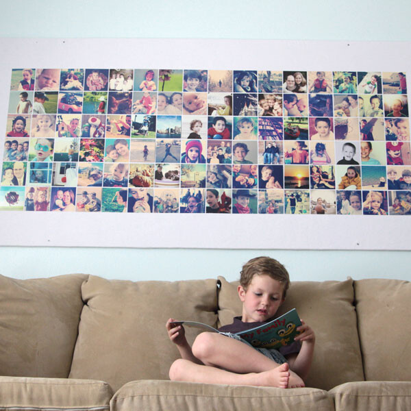A young boy sitting on a sofa in front of a giant bulletin board covered with photos